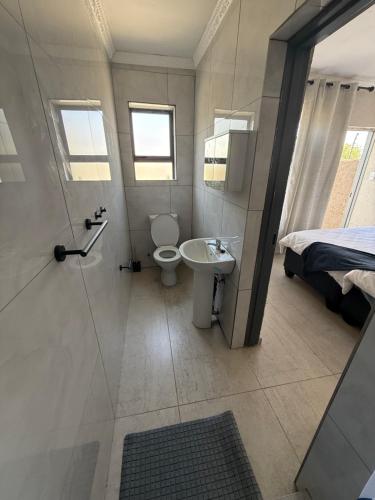 a bathroom with a toilet and a sink and a shower at The Pool_deck apartment in Lebowakgomo