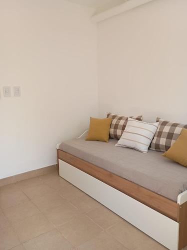 a couch against a white wall with pillows on it at Posada Atama in Gualeguaychú