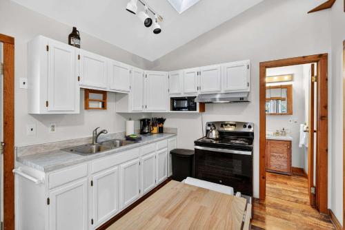 a kitchen with white cabinets and a sink and a stove at River Access Cabin with Hot Tub, Fire Pit, & WiFi! in Morton Grove