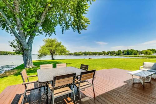 a deck with a table and chairs and a view of a lake at Month to Month and Seasonal Luxury Lakefront 5 bed 5 5 bath Estate Home in Ingleside