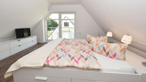 a white bedroom with a bed and a window at Exklusive Reetdach-Villa Ostseefrische in Lobbe