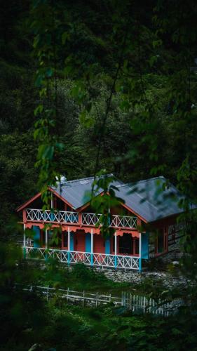 a red and blue house in the middle of a forest at Selah by soho house in Jibhi