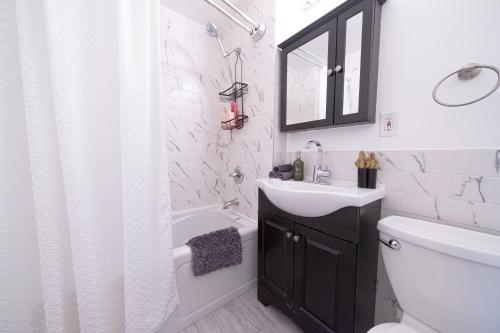 a bathroom with a sink and a toilet and a shower at Sunlit 2BR Central Park North elevator & laundry in New York