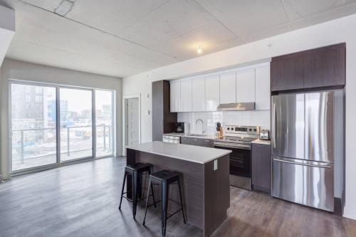 eine Küche mit Kühlschrank und Theke mit Hockern in der Unterkunft Corporate Stays Equinoxe 2 Bedroom in Chomedey