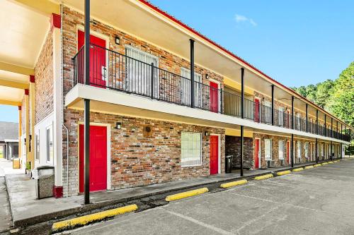 un edificio in mattoni con porte rosse e balcone di Jeffersonian Motor Inn by Townhouse, Prentiss MS a Prentiss