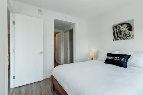 ein Schlafzimmer mit einem weißen Bett und einem schwarzen Kissen in der Unterkunft Corporate Stays Sodo 1 Bedroom in Calgary