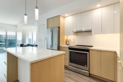 eine Küche mit weißen Schränken und einem Herd mit Backofen in der Unterkunft Corporate Stays Sodo 1 Bedroom in Calgary
