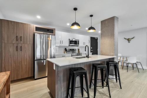 a kitchen with a sink and a counter with stools at Corporate Stays Millennium Boulevard 1 Bedroom in Moncton