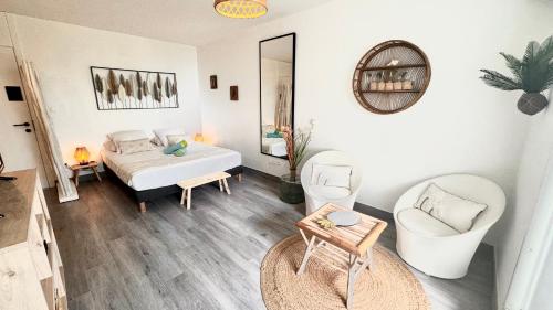1 Schlafzimmer mit einem Bett, 2 Stühlen und einem Spiegel in der Unterkunft ATOUMO vue mer avec cuve in Saint-François