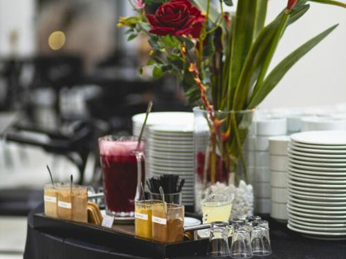 una mesa con vasos y platos y un jarrón con una flor en Favorita Golden Hotel e Eventos, en São José