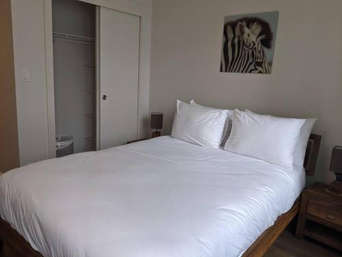 ein großes weißes Bett mit weißen Kissen im Schlafzimmer in der Unterkunft Calgary 2 Bedrooms Apartment in Calgary