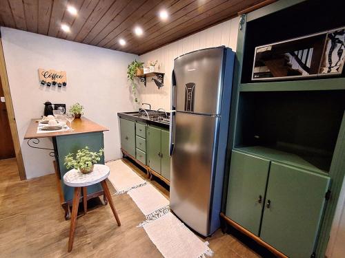 a kitchen with a stainless steel refrigerator and a table at Loft Girassol in Palhoça