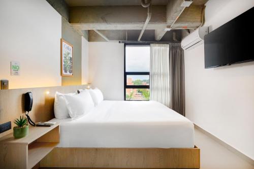a bedroom with a large white bed and a window at Hotel Attic 33 in Medellín