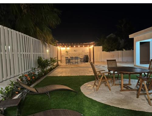 un patio trasero con una mesa y sillas y una valla en Villa Fina Aruba, en Palm-Eagle Beach