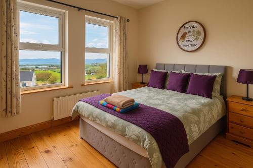 - une chambre avec un lit doté d'oreillers violets et de fenêtres dans l'établissement Heather View Cottage, à Carrigart