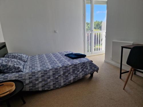 a bedroom with a bed and a table and a window at Proche rocade sud in Rennes