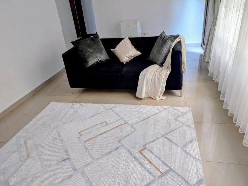 a black couch in a living room with a white rug at The Acacia Apartment in Lusaka