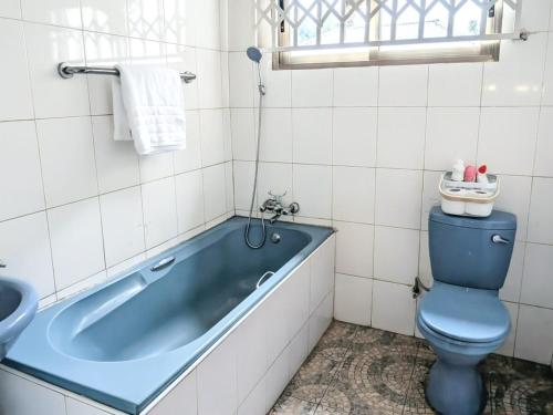 a bathroom with a blue tub and a toilet at The Acacia Apartment in Lusaka