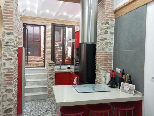 una cocina con encimera blanca y taburetes rojos en Las Golondrinas, en Galaroza