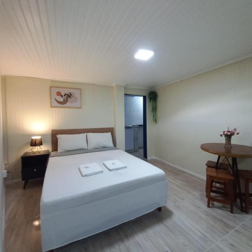 a bedroom with a large white bed and a table at Suíte Aconchegante em Hospedaria no Centro in Ouro Preto