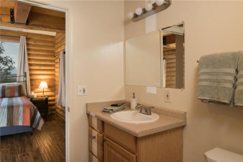 a bathroom with a sink and a bed in a room at Ontario Ave Remodeled Log Cabin on 1 Acre Gateway to Grand Canyon Amazing Views in Williams