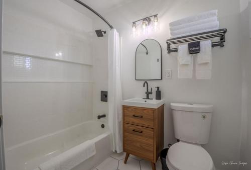 a white bathroom with a toilet and a sink at The Inn at Shady Pines in Gros Cap