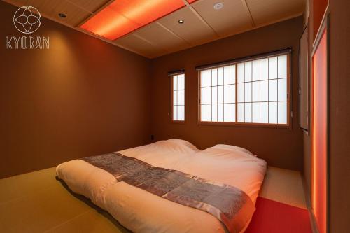 ein Schlafzimmer mit einem Bett in einem Zimmer mit zwei Fenstern in der Unterkunft Kyoran [Fuji Residence] - Vacation STAY 69041v in Kyōto