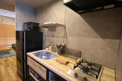 eine Küche mit einer Spüle und einem schwarzen Kühlschrank in der Unterkunft YK Mansion Sannomaru 201, 202 - Vacation STAY 70704v in Kami-kumamoto