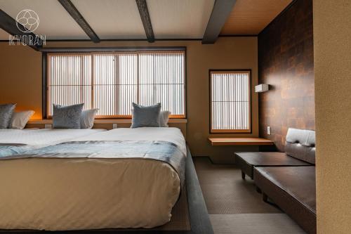 zwei Betten in einem Zimmer mit zwei Fenstern und einer Couch in der Unterkunft Kyoran [Shion Residence] - Vacation STAY 69064v in Kyōto