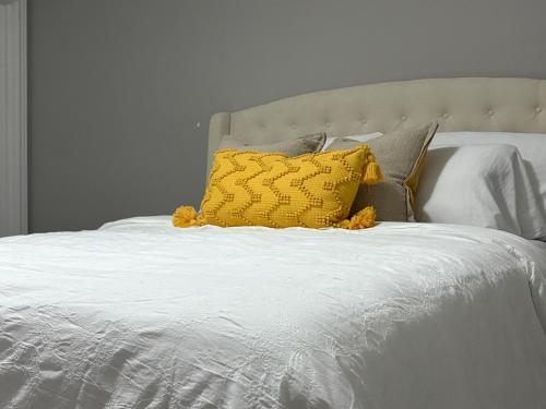 a white bed with a yellow pillow on it at Modern Private Suite close to the Airport & Border in Windsor