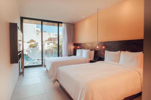 a hotel room with two beds and a balcony at CALIXTA Hotel in Playa del Carmen