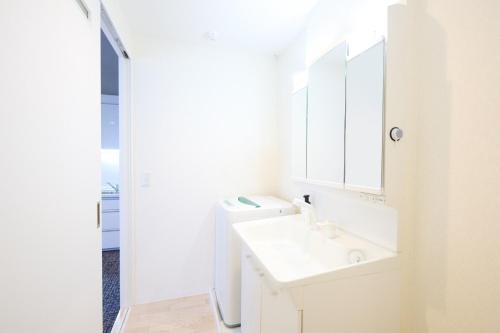 a white bathroom with a sink and a mirror at Hotel Stripe Sapporo - Vacation STAY 20494 in Kita-rokujō