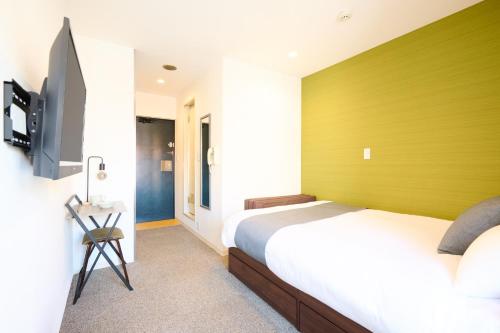 een slaapkamer met een bed met een groene muur bij Hotel Stripe Sapporo - Vacation STAY 20491 in Kita-rokujō