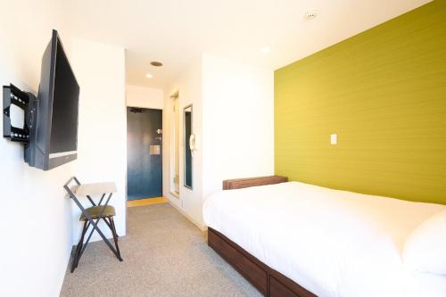 a bedroom with a bed with a green wall at Hotel Stripe Sapporo - Vacation STAY 20493 in Kita-rokujō