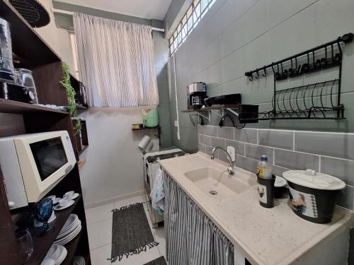 a small kitchen with a sink and a microwave at Apartamento Estúdio em Volta Redonda - RJ in Volta Redonda