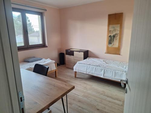 BeogradにあるWelcome dear guests!のベッド2台とテーブルと窓のある部屋