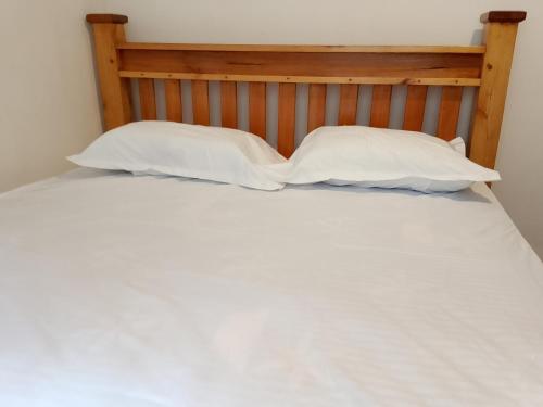 a bed with two white pillows and a wooden headboard at The Pent House Homes in Kisii