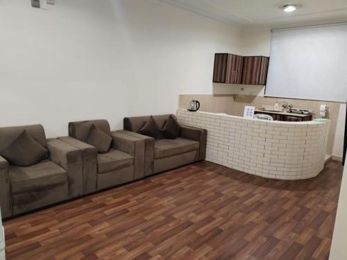 a living room with two brown couches and a kitchen at العييري للشقق المخدومة القصيم 1 in Buraydah