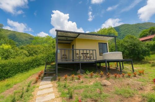 een klein huis met een balkon in een veld bij Wakana Ecosuits in Apulo