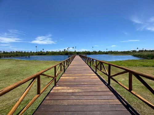 a wooden bridge over a body of water at Casa com piscina no Cond Canto do Sol - Jacuípe - Guarajuba in Camaçari