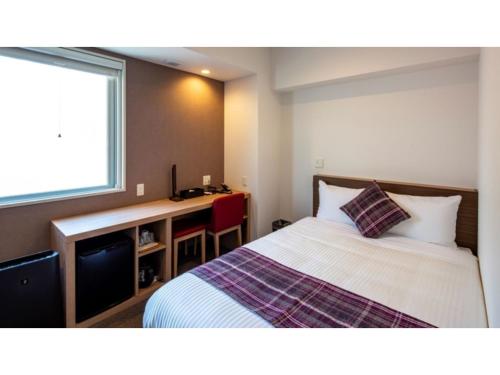 een slaapkamer met een bed, een bureau en een raam bij Hotel Reference Reisen - Vacation STAY 76456v in Fukuoka