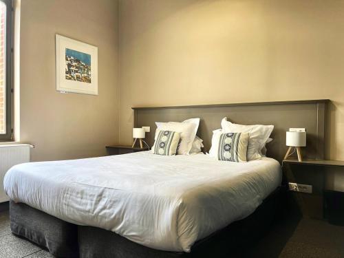 een slaapkamer met een groot wit bed met kussens bij T2 spacieux & calme - vue jardin, Amiens centre in La Celle-sous-Gouzon