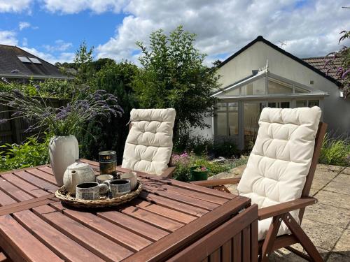 a wooden table with two white chairs and a wooden table at Bungalow on Dartmoor's Edge, Parking & Garden in Ashburton