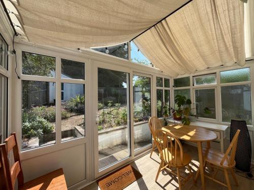a screened in porch with a table and chairs at Bungalow on Dartmoor's Edge, Parking & Garden in Ashburton