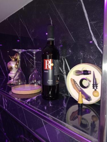 a bottle of wine sitting on a shelf with glasses at Lyon Vischi in Trani