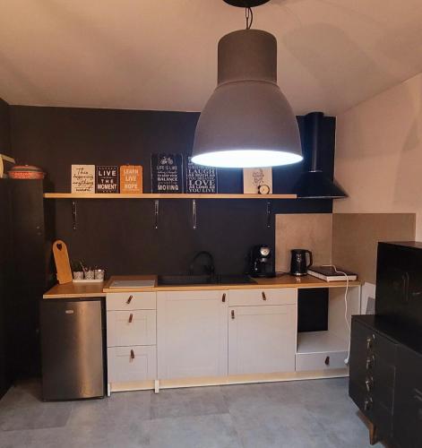 a kitchen with a large light hanging over a counter at Apartament Szpilka - domek in Police