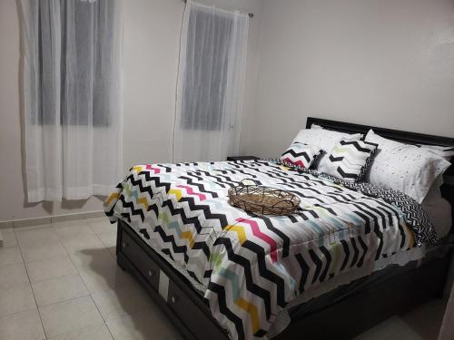 Humacao Puerto Rico house sleeps 8 في هوماكاو: غرفة نوم بسرير لحاف اسود وبيض