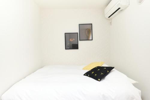ein Schlafzimmer mit einem weißen Bett mit drei Bildern an der Wand in der Unterkunft Fontaine Kamata - Vacation STAY 79354v in Tokio