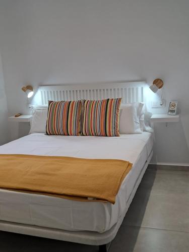 a white bed with a colorful pillow on top of it at AM Chinorros Square. in Fuengirola