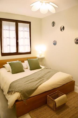 a bedroom with a bed with green pillows and a window at anthony meggy in Thiron-Gardais